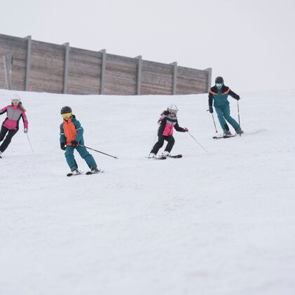Vier Skifahrer auf einer schneebedeckten Piste. | © IIC/McKINLEY