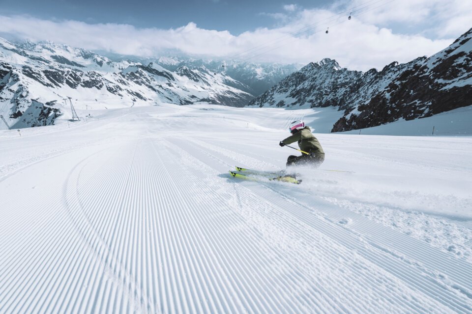 Skifahrer auf präparierter Piste in verschneiter Berglandschaft.