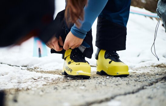 Person schnürt gelbe Skischuhe im Schnee. | © Fischer Sports GmbH
