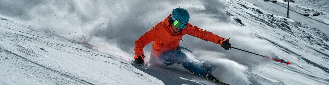 Skifahrer in orangefarbener Jacke fährt einen verschneiten Hang hinunter. | © Fischer Sports GmbH