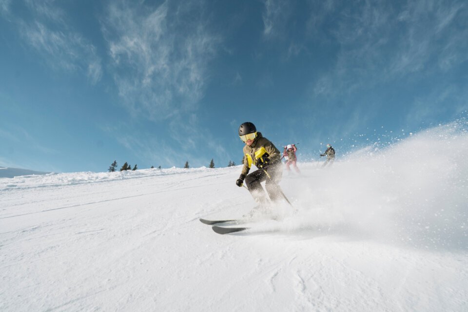 Skifahrer auf einer schneebedeckten Piste bei strahlend blauem Himmel | © INTERSPORT International Corporation GmbH