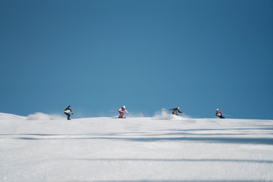 © INTERSPORT International Corporation GmbH Gruppe von Skifahrern auf einer schneebedeckten Piste unter blauem Himmel. | © INTERSPORT International Corporation GmbH