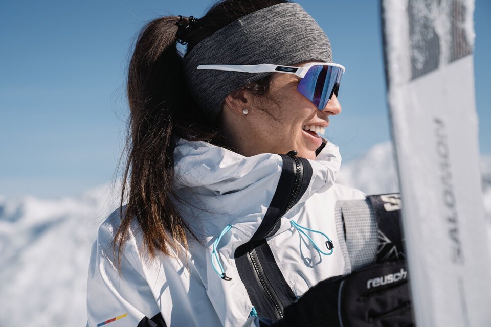 Frau mit Sonnenbrille und Skiausrüstung lächelt | © INTERSPORT International Corporation GmbH