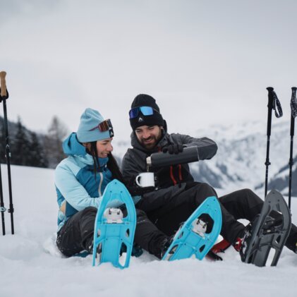 Ein Paar macht eine Pause beim Schneeschuhwandern und trinkt Kaffee. | © INTERSPORT International Corporation GmbH