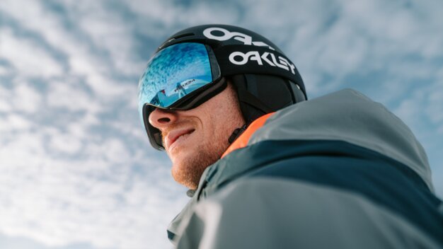 Skifahrer mit Oakley-Helm und Brille blickt in die Ferne.