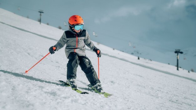 Kind fährt Ski auf einer verschneiten Piste.