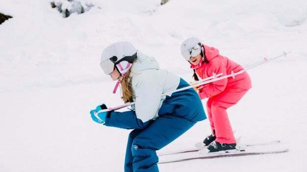 Zwei Mädchen beim Skifahren im Schnee.
