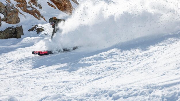 Skifahrer im Tiefschnee mit aufgewirbeltem Schnee.