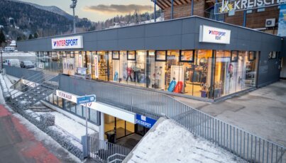 INTERSPORT Rent Shopgebäude an einer Talstation mit großen Schaufenstern und Zugang über eine Außentreppe